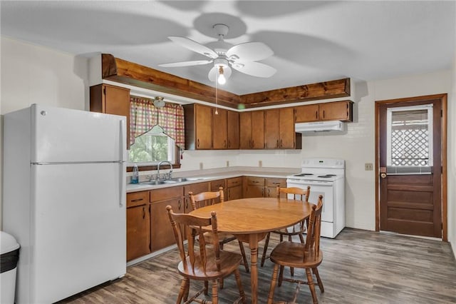 310 E Clay St, Carrollton, MO 64633 - kitchen with white appliances, under cabinet range hood, wood finished floors, light countertops, and brown cabinets