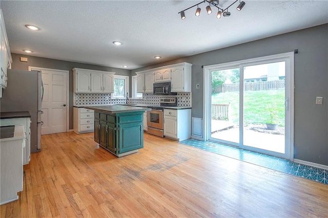 9705 N Virginia Ave, Kansas City, MO 64155 - kitchen with stainless steel appliances, backsplash, light wood finished floors, dark countertops, and white cabinetry
