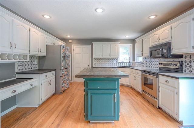9705 N Virginia Ave, Kansas City, MO 64155 - kitchen featuring stainless steel appliances, white cabinets, a center island, backsplash, and light wood-type flooring