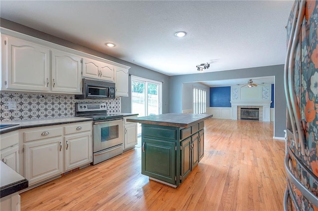 9705 N Virginia Ave, Kansas City, MO 64155 - kitchen featuring black microwave, stainless steel electric stove, white cabinets, a glass covered fireplace, and dark countertops