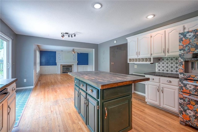 9705 N Virginia Ave, Kansas City, MO 64155 - kitchen with white cabinetry, a ceiling fan, light wood-style flooring, a kitchen island, and a textured ceiling