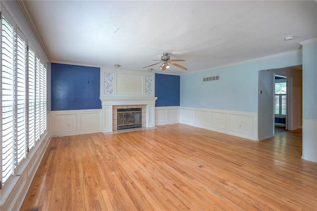 9705 N Virginia Ave, Kansas City, MO 64155 - unfurnished living room featuring a decorative wall, a ceiling fan, crown molding, light wood-style floors, and a tiled fireplace