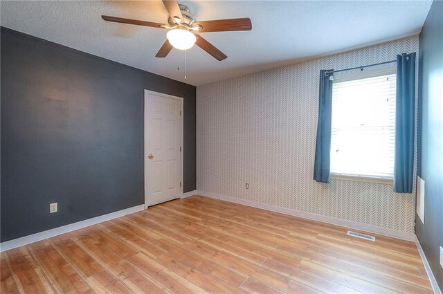 9705 N Virginia Ave, Kansas City, MO 64155 - empty room with wallpapered walls, light wood finished floors, and a ceiling fan