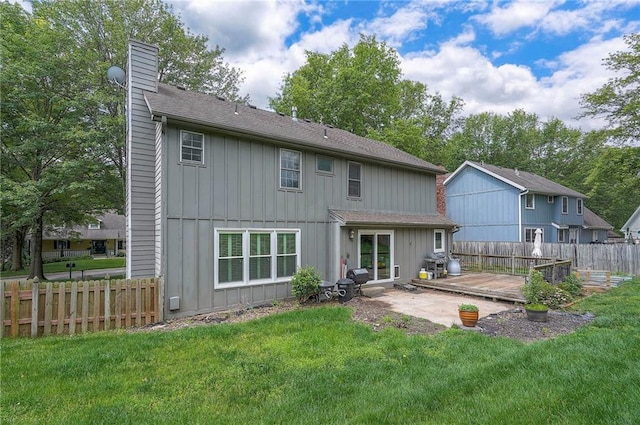 9705 N Virginia Ave, Kansas City, MO 64155 - back of property with a chimney, a fenced backyard, board and batten siding, roof with shingles, and a deck