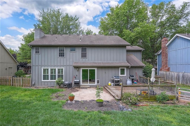9705 N Virginia Ave, Kansas City, MO 64155 - back of property featuring a chimney, a fenced backyard, a shingled roof, a patio, and a wooden deck