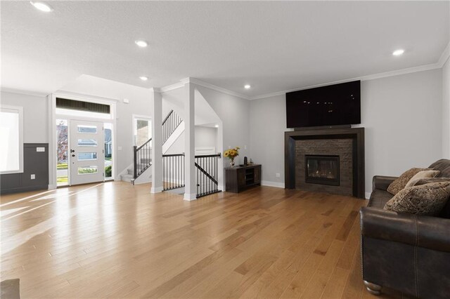 3113 SW Arboridge Dr, Lees Summit, MO 64081 - living room featuring light wood-type flooring, ornamental molding, recessed lighting, stairs, and a stone fireplace