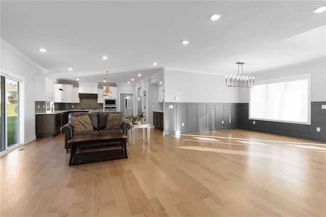 3113 SW Arboridge Dr, Lees Summit, MO 64081 - living room featuring a chandelier, ornamental molding, light wood-style flooring, a wainscoted wall, and recessed lighting