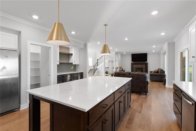 3113 SW Arboridge Dr, Lees Summit, MO 64081 - kitchen with stainless steel appliances, ornamental molding, dark brown cabinetry, light countertops, and light wood-style flooring