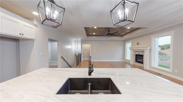 22902 S Ridgeview Dr, Peculiar, MO 64078 - kitchen with a chandelier, a tray ceiling, open floor plan, light stone counters, and ornamental molding