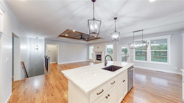 22902 S Ridgeview Dr, Peculiar, MO 64078 - kitchen with light wood-style floors, a stone fireplace, white cabinets, a ceiling fan, and pendant lighting