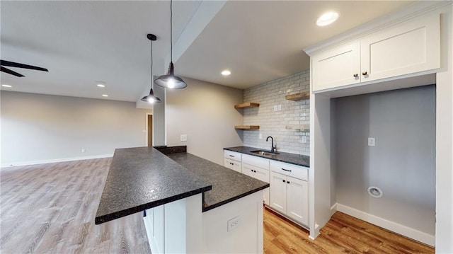 22902 S Ridgeview Dr, Peculiar, MO 64078 - kitchen with dark countertops, decorative backsplash, white cabinetry, light wood-style flooring, and hanging light fixtures