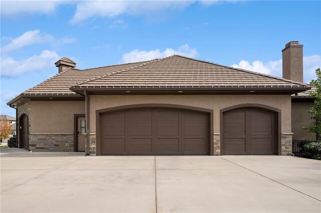 14713 Ash St, Leawood, KS 66224 - view of front facade featuring stone siding, a garage, and a chimney