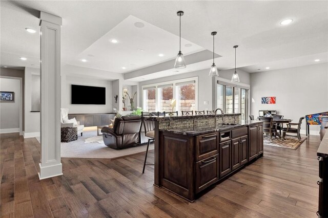 14713 Ash St, Leawood, KS 66224 - kitchen featuring a breakfast bar, decorative columns, dark wood-type flooring, and recessed lighting