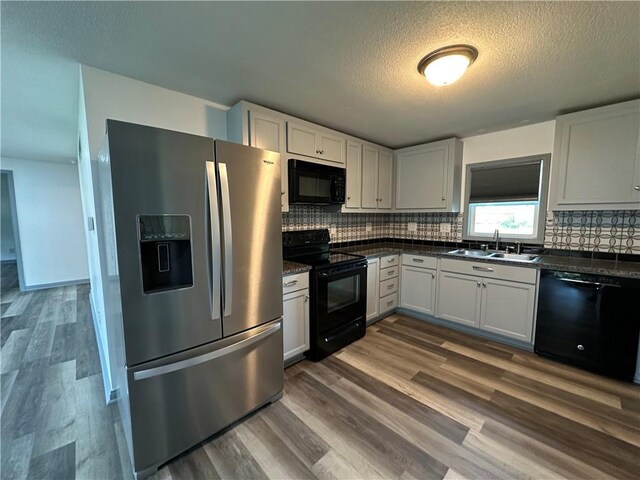 1915 W 5th St, Sedalia, MO 65301 - kitchen featuring black appliances, dark countertops, backsplash, dark wood finished floors, and a textured ceiling
