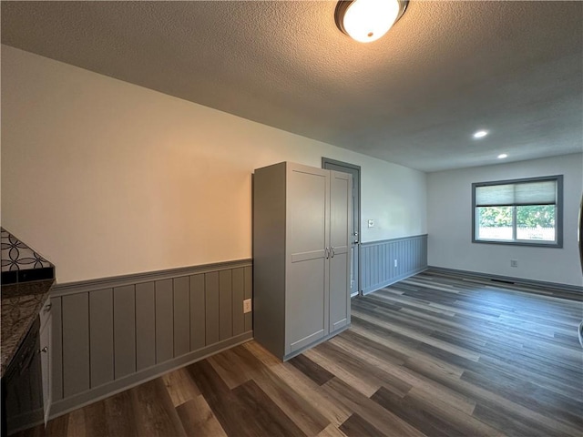 1915 W 5th St, Sedalia, MO 65301 - empty room featuring a wainscoted wall, dark wood-style floors, a textured ceiling, and recessed lighting