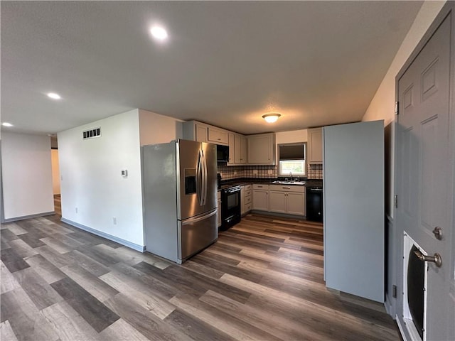 1915 W 5th St, Sedalia, MO 65301 - kitchen with black appliances, dark wood-type flooring, dark countertops, recessed lighting, and backsplash