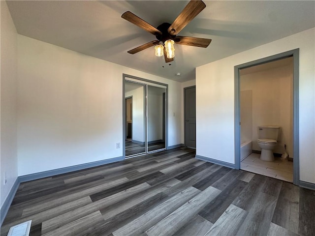 1915 W 5th St, Sedalia, MO 65301 - unfurnished bedroom featuring dark wood finished floors, a closet, a ceiling fan, and ensuite bath