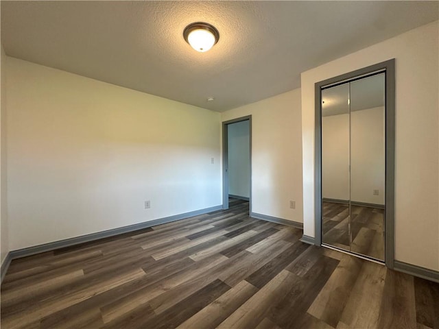 1915 W 5th St, Sedalia, MO 65301 - unfurnished bedroom with dark wood-style flooring, a closet, and a textured ceiling