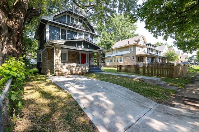 3428 College Ave, Kansas City, MO 64128 - american foursquare style home featuring a porch, stone siding, and a residential view