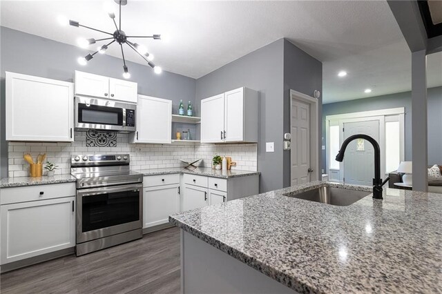 3428 College Ave, Kansas City, MO 64128 - kitchen with stainless steel appliances, open shelves, white cabinetry, tasteful backsplash, and dark wood-style flooring