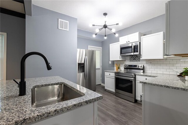 3428 College Ave, Kansas City, MO 64128 - kitchen featuring stainless steel appliances, a chandelier, tasteful backsplash, and light stone counters
