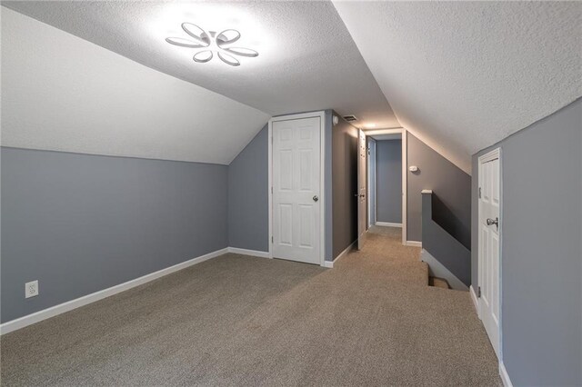 3428 College Ave, Kansas City, MO 64128 - additional living space with a textured ceiling, carpet, and vaulted ceiling