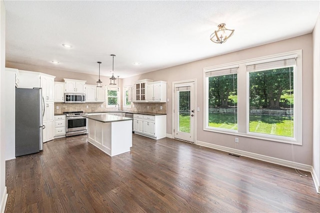 4824 W 162nd St, Overland Park, KS 66085 - kitchen with appliances with stainless steel finishes, decorative backsplash, white cabinets, dark wood finished floors, and a center island