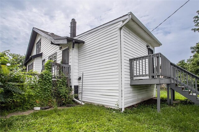 4600 Chestnut Ave, Kansas City, MO 64130 - view of side of home with stairway, a chimney, a deck, and a yard