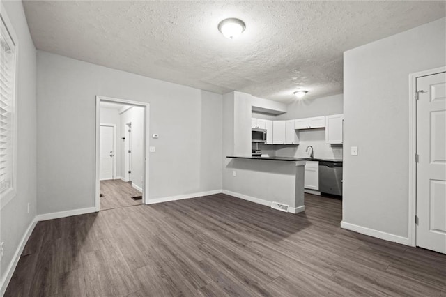520 Sandusky Ave, Kansas City, KS 66101 - kitchen featuring stainless steel appliances, dark wood-style flooring, dark countertops, white cabinetry, and a textured ceiling