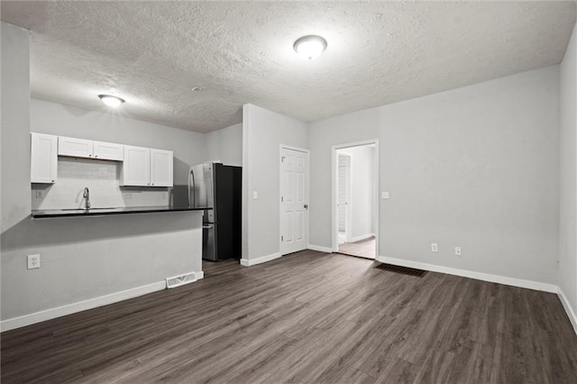 520 Sandusky Ave, Kansas City, KS 66101 - kitchen with dark countertops, white cabinetry, freestanding refrigerator, a textured ceiling, and dark wood-type flooring
