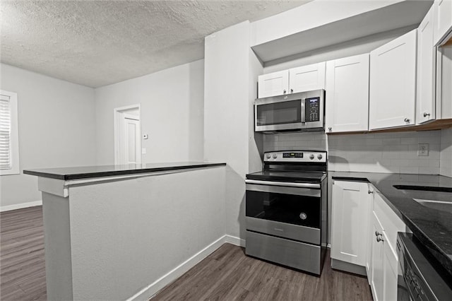 520 Sandusky Ave, Kansas City, KS 66101 - kitchen featuring stainless steel appliances, dark wood-style flooring, decorative backsplash, white cabinets, and a textured ceiling