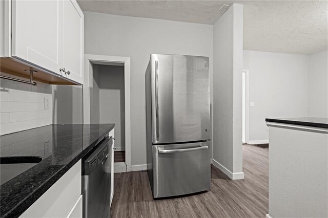 520 Sandusky Ave, Kansas City, KS 66101 - kitchen with stainless steel appliances, wood finished floors, tasteful backsplash, white cabinetry, and dark stone countertops