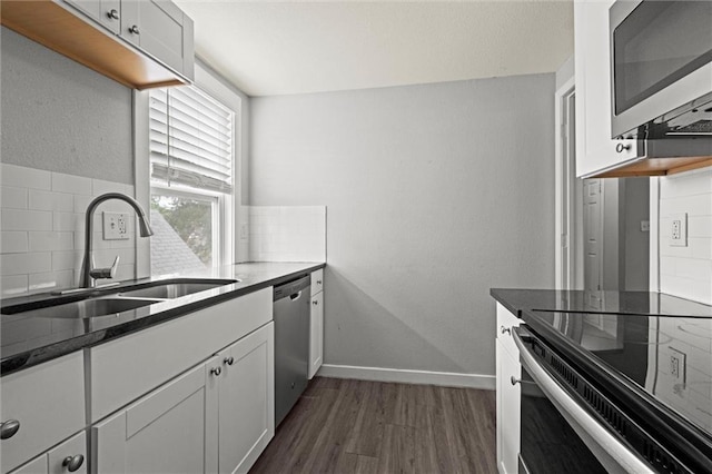 520 Sandusky Ave, Kansas City, KS 66101 - kitchen with appliances with stainless steel finishes, tasteful backsplash, dark wood-style flooring, white cabinetry, and dark stone counters