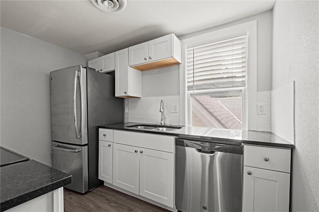 520 Sandusky Ave, Kansas City, KS 66101 - kitchen featuring stainless steel appliances, dark wood-type flooring, white cabinets, backsplash, and a textured wall