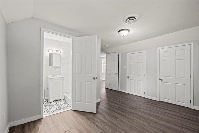 520 Sandusky Ave, Kansas City, KS 66101 - unfurnished bedroom with dark wood-style floors, vaulted ceiling, and ensuite bath