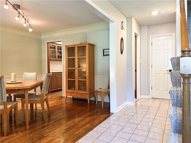 4117 NE Edgewater Ct, Lees Summit, MO 64064 - dining room with a textured ceiling, light wood-style floors, a wainscoted wall, ornamental molding, and rail lighting