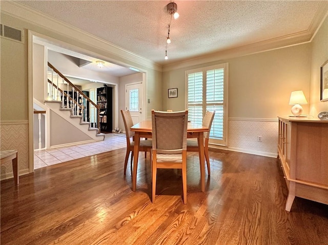4117 NE Edgewater Ct, Lees Summit, MO 64064 - dining room with wainscoting, wood finished floors, stairs, a textured ceiling, and crown molding