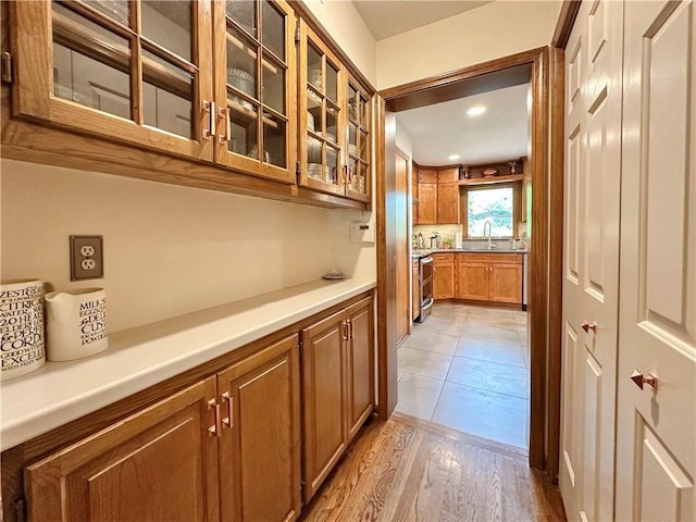 4117 NE Edgewater Ct, Lees Summit, MO 64064 - kitchen with brown cabinetry, glass insert cabinets, light wood-style flooring, light countertops, and recessed lighting