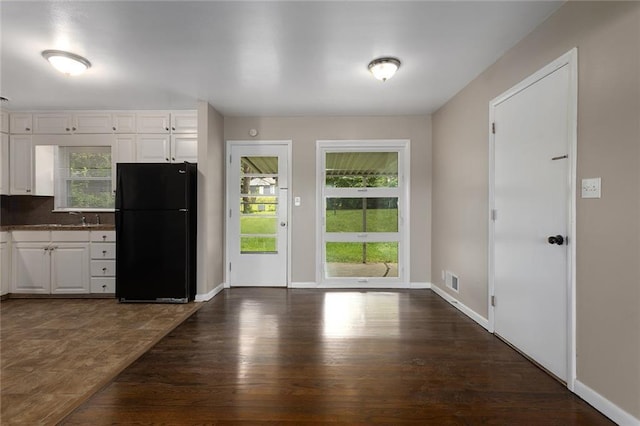 1219 W 35th St, Independence, MO 64055 - kitchen featuring freestanding refrigerator, healthy amount of natural light, white cabinets, and dark wood finished floors