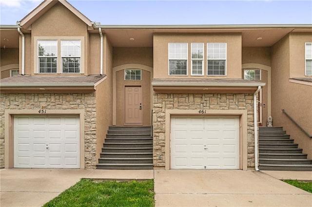 461 S Woodson Ln, Gardner, KS 66030 - townhome / multi-family property featuring driveway, stucco siding, an attached garage, and stone siding