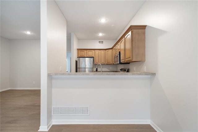 461 S Woodson Ln, Gardner, KS 66030 - kitchen featuring appliances with stainless steel finishes, wood finished floors, recessed lighting, light countertops, and a peninsula