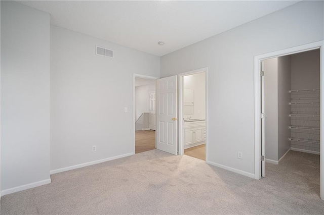 461 S Woodson Ln, Gardner, KS 66030 - unfurnished bedroom featuring light colored carpet, a spacious closet, ensuite bath, and a closet