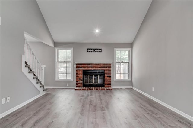 12321 W 105th Ter, Overland Park, KS 66215 - unfurnished living room featuring vaulted ceiling, healthy amount of natural light, wood finished floors, stairway, and a fireplace
