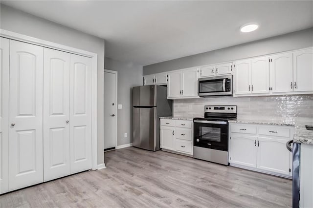 12321 W 105th Ter, Overland Park, KS 66215 - kitchen with appliances with stainless steel finishes, white cabinets, tasteful backsplash, and light stone counters
