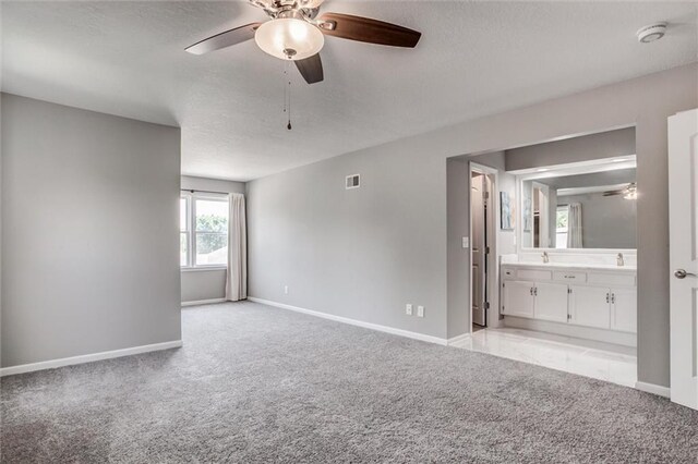 12321 W 105th Ter, Overland Park, KS 66215 - unfurnished bedroom with light colored carpet, a textured ceiling, connected bathroom, and a ceiling fan