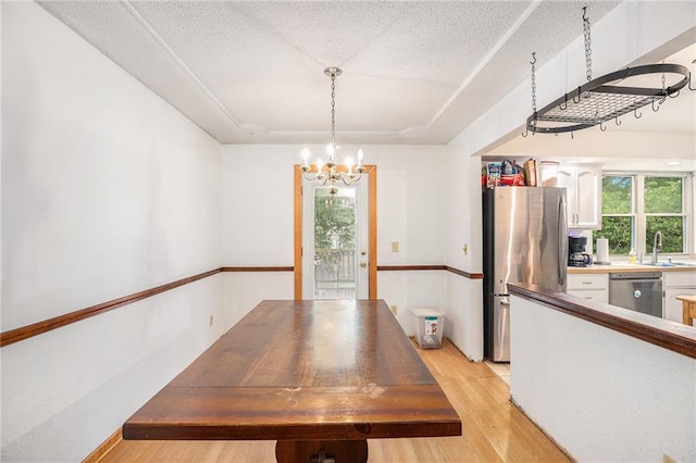 1422 S Kiowa Dr, Olathe, KS 66062 - unfurnished dining area featuring light wood-type flooring, a chandelier, and a textured ceiling