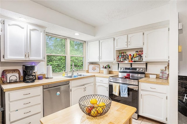1422 S Kiowa Dr, Olathe, KS 66062 - kitchen featuring appliances with stainless steel finishes, white cabinets, light countertops, a textured ceiling, and light tile patterned floors