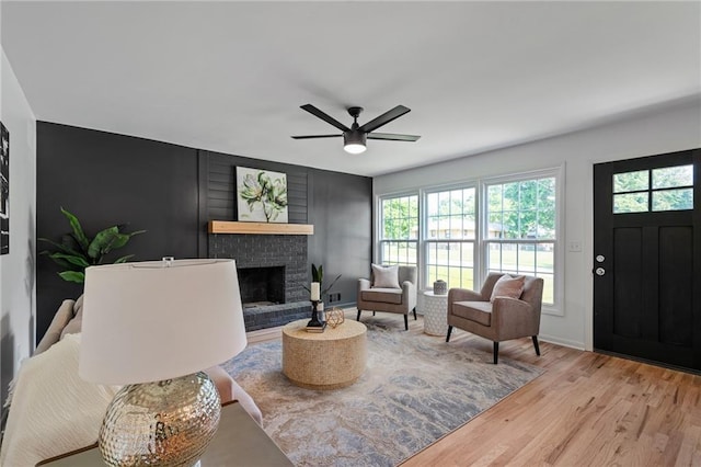 811 NW Maynard St, Blue Springs, MO 64015 - living room featuring light wood finished floors, a brick fireplace, and a ceiling fan