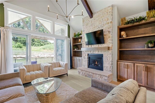 1128 Hillswick Ln, Raymore, MO 64083 - living area featuring a chandelier, light wood finished floors, beam ceiling, a stone fireplace, and high vaulted ceiling