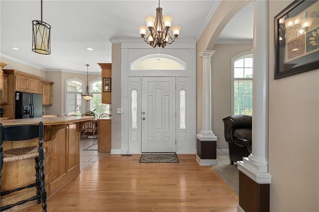 4148 SE Paddock Dr, Lees Summit, MO 64082 - foyer entrance featuring arched walkways, a chandelier, ornate columns, light wood-style flooring, and ornamental molding